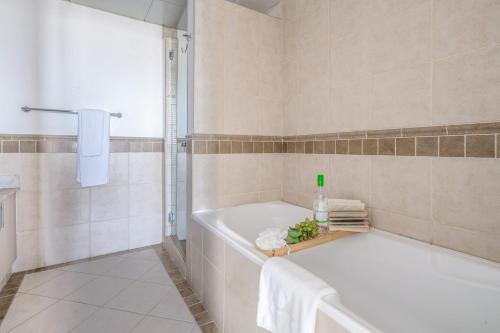 a white bathroom with a tub and a shower at Frank Porter - Al Badia 2 in Dubai