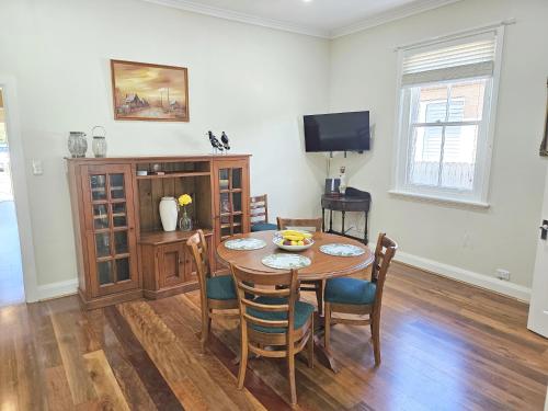 a dining room with a table and chairs and a television at Araluen, Heart of Bowral in Bowral