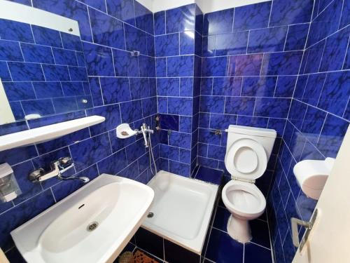 a blue tiled bathroom with a toilet and a sink at Excelsior in Eforie Sud