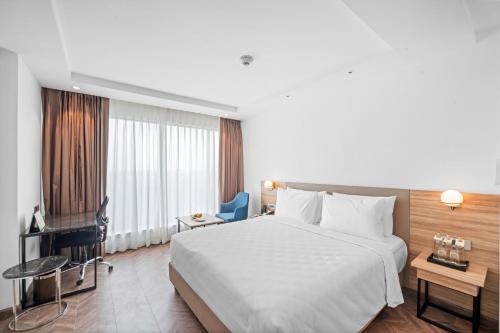 a hotel room with a large white bed and a desk at Grand Vijayawada by GRT Hotels in Vijayawāda