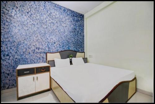 1 dormitorio con cama blanca y pared azul en HOTEL SATYAM SHREE, en Indore