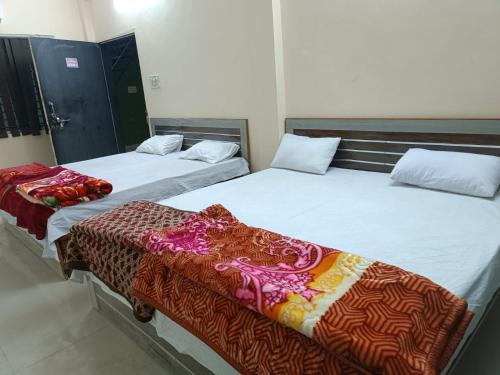 dos camas sentadas una al lado de la otra en una habitación en HOTEL SATYAM SHREE, en Indore