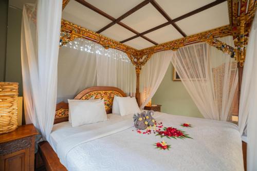 a bedroom with a white bed with flowers on it at Honeymoon Guesthouse in Ubud