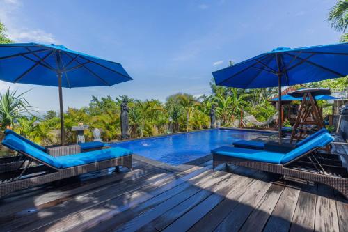 a pool at a resort with blue chairs and umbrellas at Tatak Bunut Villa Ceningan in Nusa Lembongan