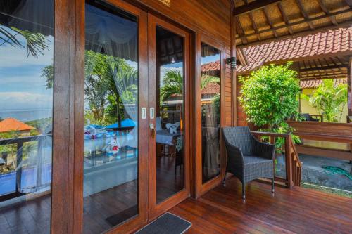 an open porch with a chair and a view of the ocean at Tatak Bunut Villa Ceningan in Nusa Lembongan