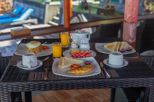a table with plates of breakfast food on it at Tatak Bunut Villa Ceningan in Nusa Lembongan