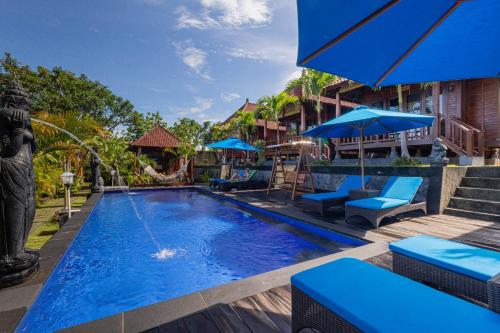 a pool at a resort with blue chairs and umbrellas at Tatak Bunut Villa Ceningan in Nusa Lembongan