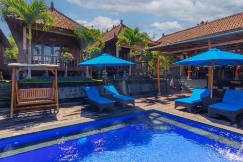 レンボンガン島にあるTatak Bunut Villa Ceninganの家の隣のプール(青い椅子、パラソル付)