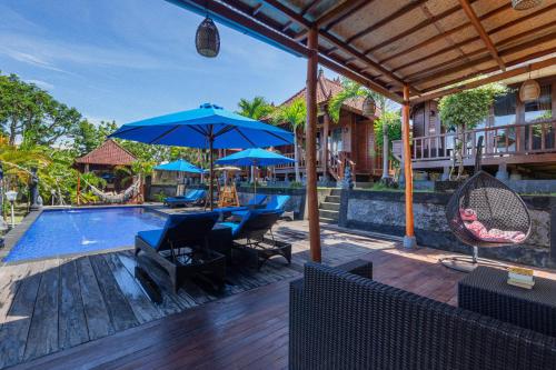 an outdoor patio with a pool and blue umbrellas at Tatak Bunut Villa Ceningan in Nusa Lembongan