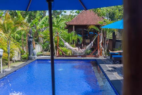 a pool with a hammock and a house at Tatak Bunut Villa Ceningan in Nusa Lembongan