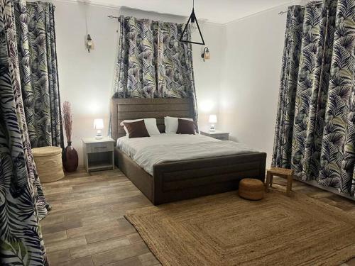 a bedroom with a bed and two tables and curtains at Trou aux Biches Serenity in Pointe aux Biches