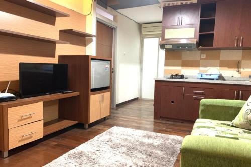 un soggiorno con TV e cucina di OYO 93585 Apartemen Cibubur Village By Raja Property a Depok