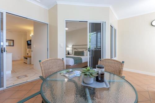a glass table and chairs in a room with a bed at The Newport on Macrossan - Adults Only in Port Douglas