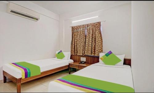 1 dormitorio con 2 camas y ventana en The Trinitywood Hotel Restaurants en Bangalore