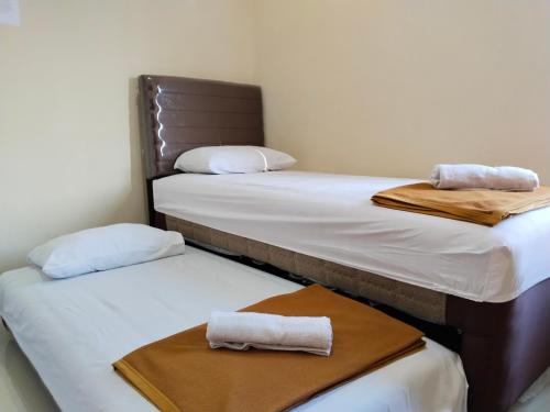 drie bedden in een kamer met handdoeken erop bij U Eleven Syariah Homestay in Tangerang