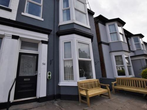 two benches in front of a house with a door at Victorian Suites in Southport