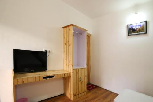 a living room with a flat screen tv on a wooden shelf at Hotel Lhalingkha in Leh