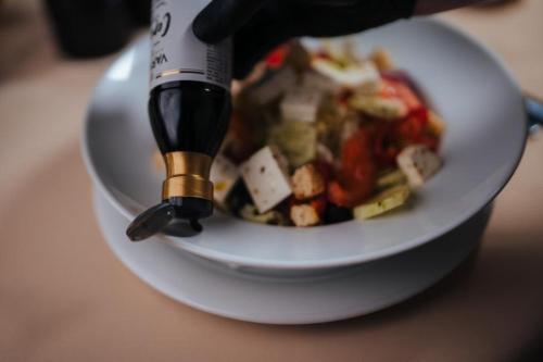 a person holding a wine bottle in a bowl of food at Podu' cu Lanturi in Bacău
