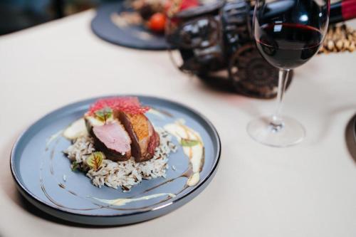 a plate of food with rice and a glass of wine at Podu' cu Lanturi in Bacău