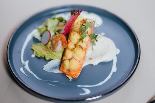 a blue plate with a piece of shrimp and a salad at Podu' cu Lanturi in Bacău