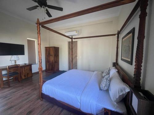a bedroom with a canopy bed and a desk at Tiger Retreat in Sawāi Mādhopur
