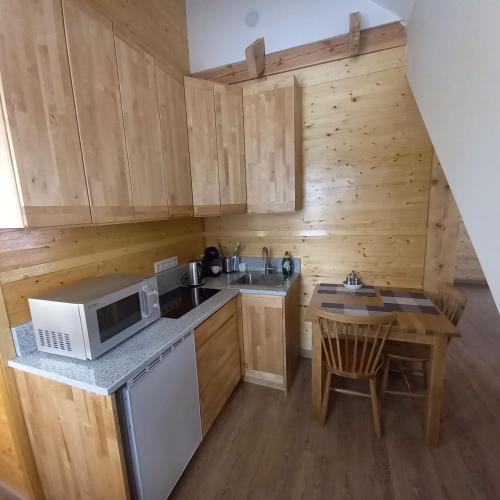 a kitchen with wooden cabinets and a table and a microwave at S Neries 19 apartamentai su parkingu in Šiauliai