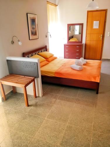 a bedroom with a bed with a bench and a mirror at Nikos Apartments in Ormos Panagias