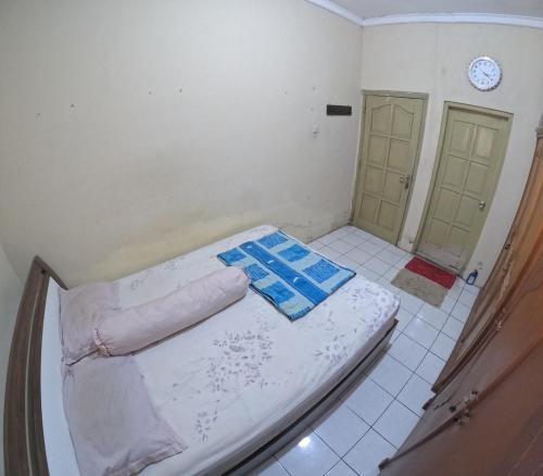 a small bedroom with a bed and a clock on the wall at Omah Tegalrejo Family Only in Jetis