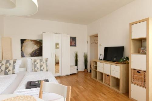 een woonkamer met een witte bank en een televisie bij Modern Vienna Apartment in Prime Location in Wenen