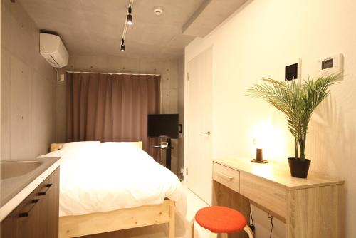 a bedroom with a bed and a desk with a plant at Tokyo Time Traveler 駅徒歩5分 暮らすように泊まれるホテル in Tokyo