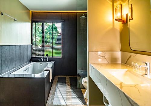 a bathroom with a tub and a sink and a toilet at Pelangi Beach Resort & Spa, Langkawi in Pantai Cenang