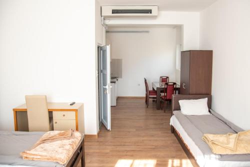 a room with two beds and a desk and a table at Apartments Kuca Aleksic in Niš