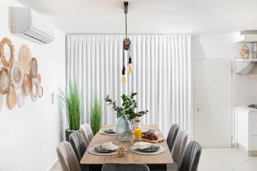 a dining room with a wooden table and chairs at By Eezy- דירה משפחתית מפנקת 3 חדרי שינה - Hanechoshet in Eilat