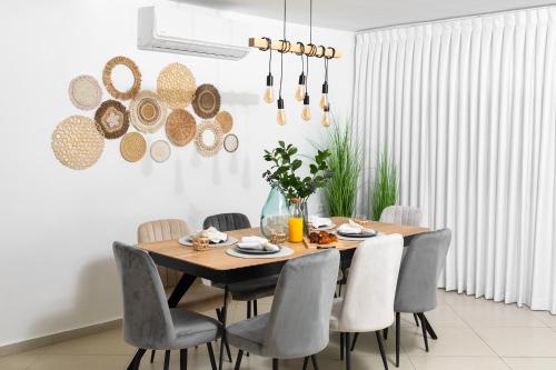 a dining room with a wooden table and chairs at By Eezy- דירה משפחתית מפנקת 3 חדרי שינה - Hanechoshet in Eilat