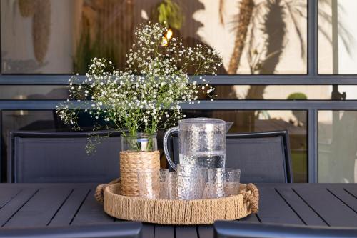 a table with a vase of flowers and glasses on it at By Eezy- דירה משפחתית מפנקת 3 חדרי שינה - Hanechoshet in Eilat