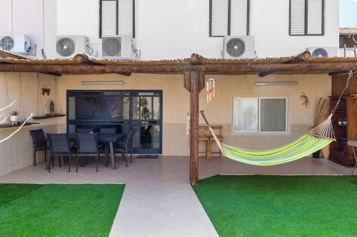 a patio with a hammock and a table and chairs at By Eezy- דירה משפחתית מפנקת 3 חדרי שינה - Hanechoshet in Eilat