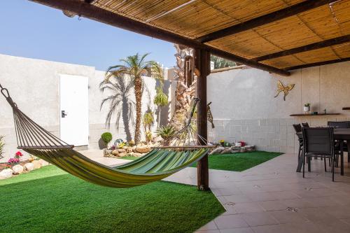 a hammock in the middle of a patio at By Eezy- דירה משפחתית מפנקת 3 חדרי שינה - Hanechoshet in Eilat