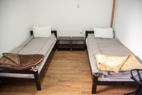 two twin beds in a room with wooden floors at Apartments Kuca Aleksic in Niš