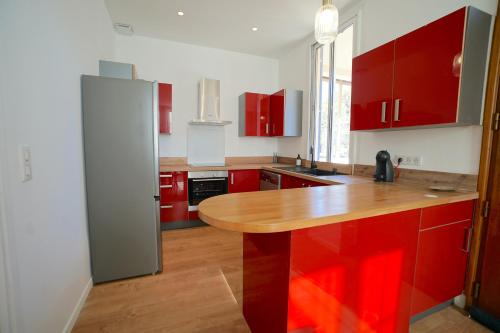une cuisine avec des placards rouges et un comptoir en bois dans l'établissement Magnifique haut de villa chez Charlotte, à Antibes
