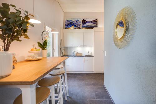 a kitchen with a wooden table and stools at Bijou du Lac - mit Pool und Privatstrand in Därligen
