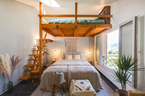 - une chambre avec un lit dans une pièce avec une mezzanine dans l'établissement Bijou du Lac - mit Pool und Privatstrand, à Därligen