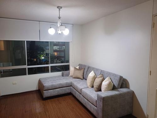 a living room with a gray couch and a window at Habitación acogedora Orué in Lima