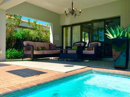 una piscina con sillas y una mesa en una casa en Westlake Waterfront Villa - Entire Villa, en Hartbeespoort