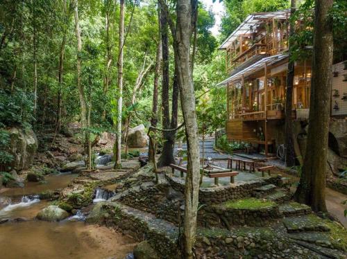a house in the woods next to a river at Woo Ma Ca Moo in Chiang Mai