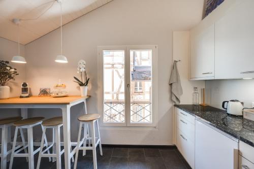 a kitchen with white cabinets and a counter with stools at Bijou du Lac - mit Pool und Privatstrand in Därligen