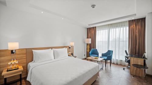 a hotel room with a bed and a desk and chairs at Grand Vijayawada by GRT Hotels in Vijayawāda