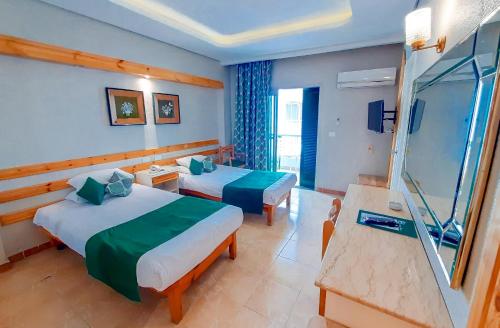 a hotel room with two beds and a television at Beau Site Hotel in Marsa Matruh