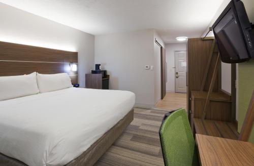 a hotel room with a bed and a flat screen tv at Holiday Inn Express & Suites Minneapolis - West End by IHG in Minneapolis