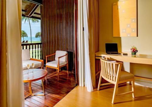 a living room with a desk and a table and chairs at Pelangi Beach Resort & Spa, Langkawi in Pantai Cenang