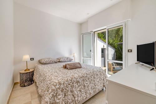 a white bedroom with a bed and a large window at Villa Athéna - Villa dexception vue montagne in Mougins
